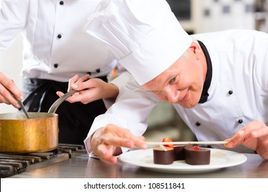 Cook, The Pastry Chef, In Hotel Or Restaurant Kitchen Cooking, He Is Finishing A Sweet Dessert