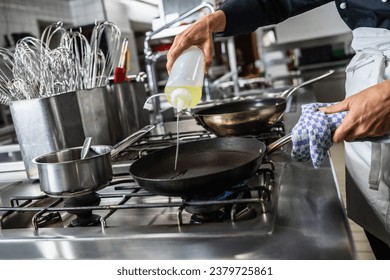 cook pouring Oil into a Heated pan at a restaurant. Luxury hotel cooking concept image. - Powered by Shutterstock