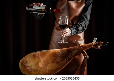 The cook pours the wine into a glass. A bottle of wine, Spanish jamon and traditional food, - Shutterstock ID 2035088435