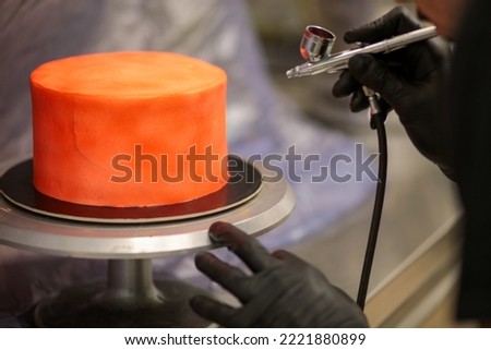 cook preparing a red frosted cake using air bush