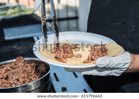 Cook puts the meat into the tacos