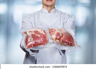 Cook shows Packed meat on blurred background.