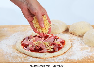 Cook Sprinkling Shredded Cheese Over Pizza
