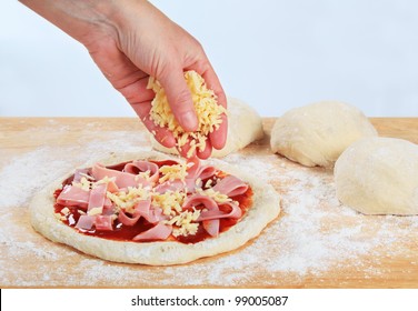 Cook Sprinkling Shredded Cheese Over Pizza
