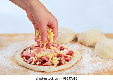 Cook Sprinkling Shredded Cheese Over Pizza
