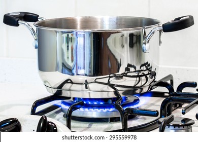 cook with a steel pot on the stove in the kitchen