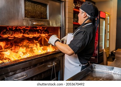 Cook stoking the fire for cooking stack of grilled chicken on a skewer in a restaurant.