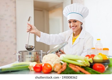  Cook In White Uniform Tests  Soup With Ladle At Commercial Kitchen  