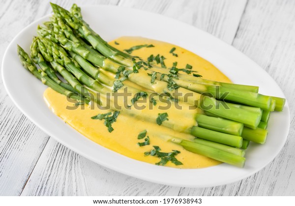 Cooked asparagus with Hollandaise sauce on the\
serving plate