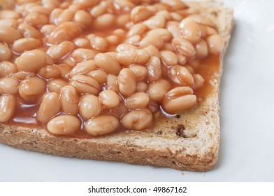 Cooked Baked Beans On Wholemeal Granary Toast Shot In Close Up And Cutting Off At Left Frame.  Plate Showing To Right And Below.
