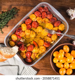 Cooked baked cherry tomatoes with garlic, thyme and pepper and olive oil in a baking sheet - making French homemade tomato confit, top view