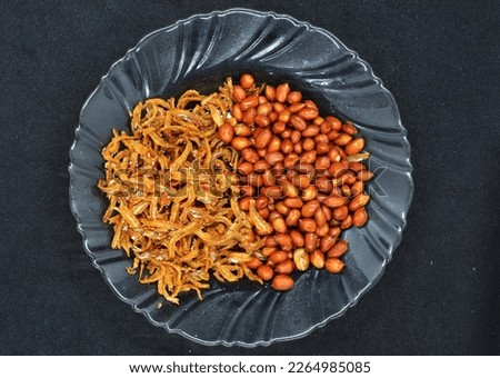 cooked beans and anchovies on a dark backdrop, top view

