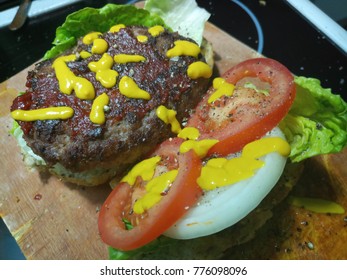 Cooked beef burger preparing with tomatoes, lettuce, onions and mustard 