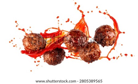 Cooked beef meatballs flying dynamically with splashing red tomato sauce isolated on a white background