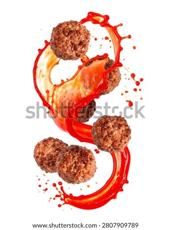 Cooked beef meatballs flying dynamically with splashing red tomato sauce isolated on a white background