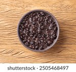 Cooked black beans in a bowl over wooden table.