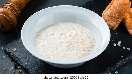 Cooked boiled white oatmeal. Garnish boiled oatmeal porridge with milk in a plate.