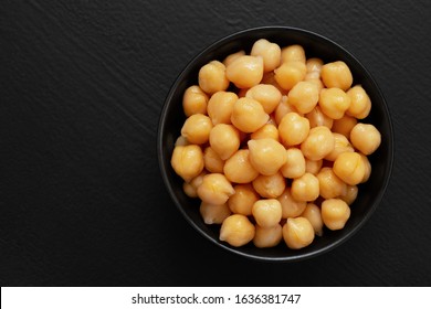 Cooked Chick Peas In A Black Ceramic Bowl Isolated On Black Painted Wood. Top View.