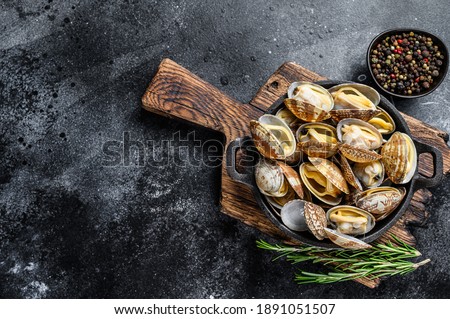 Cooked Clams vongole in a pan. Black background. Top view. Copy space.