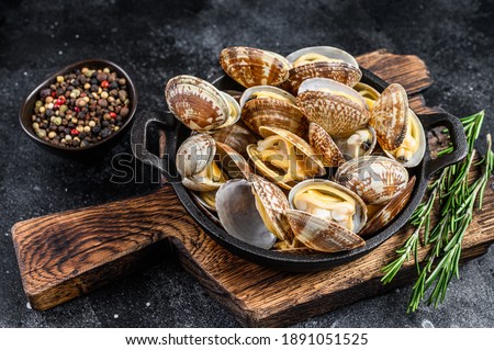 Cooked Clams vongole in a pan. Black background. Top view.