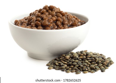 Cooked French Green Puy Lentils In White Ceramic Bowl Next To Dry Lentils Isolated On White. Low Angle.
