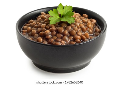 Cooked French Green Puy Lentils With Garnish In Black Ceramic Bowl Isolated On White. High Angle.