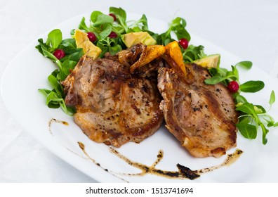 Cooked fried pork meat chops with with greens, avocado and berries at plate
