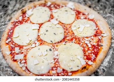 Cooked Frozen Whole Small Pizza Crust On Table With Melted Mozzarella Provolone Cheese And Sprinkles And Red Tomato Sauce .closeup As Italian Food Cuisine Storebought