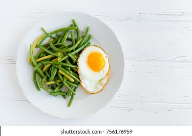 Cooked Green Beans With Fried Egg In White Plate On Wooden Background With Space For Text. Healthy Vegetarian Food Concept. Top View. Copy Space.