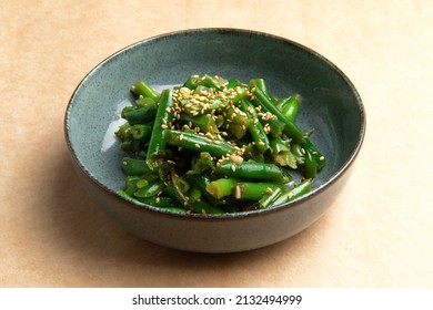 Cooked green beans in a plate on a brown background. Selective focus.