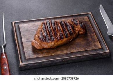 Cooked Grilled Chuck Eye Roll Steak On A Chopping Board. Dark Background