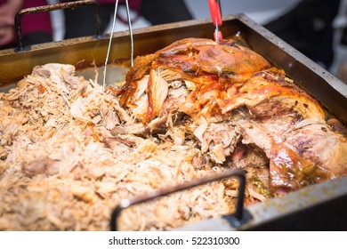 Cooked hog roast pulled pork on a large metal serving tray