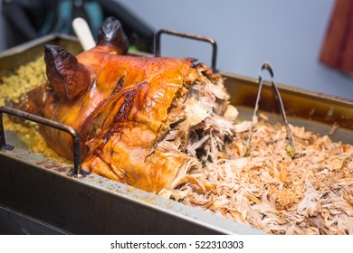 Cooked hog roast pulled pork on a large metal serving tray