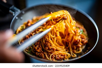 Cooked Italian spaghetti being put into hot bolognese sauce in the pan on kitchen - Powered by Shutterstock