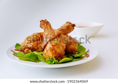 Cooked legs of chicken with spinach on white plate. Balanced meal.