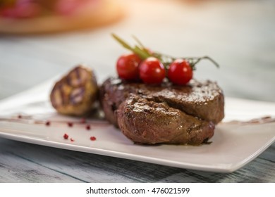 Cooked meat and garlic. Small tomatoes of red color. Tenderloin steak of veal. Have lunch in local cafe. - Shutterstock ID 476021599