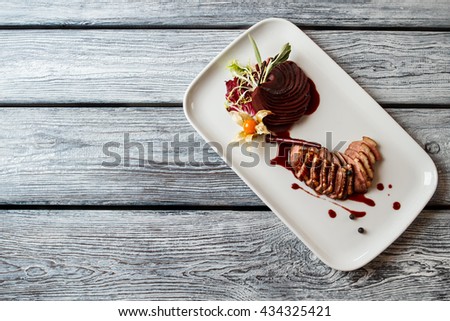 Cooked meat on plate. Dish with sauce and herb. Cinnamon stick and duck breast. Lunch for a gourmet.