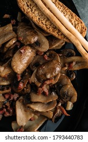 Cooked mushrroms with ham pieces on a black plate