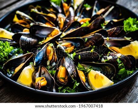 Cooked mussels with lemon and parsley on wooden table 