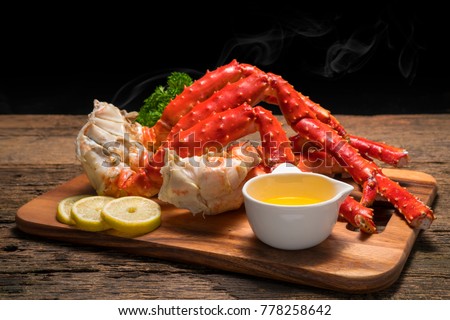 Cooked Organic Alaskan King Crab Legs with Butter and lemons, Alaskan King Crab on vintage wooden background.