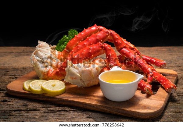 Cooked Organic Alaskan\
King Crab Legs with Butter and lemons, Alaskan King Crab on vintage\
wooden background.