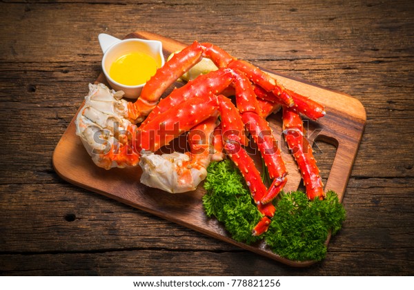 Cooked Organic Alaskan\
King Crab Legs with Butter and lemons,Alaskan King Crab on vintage\
wooden background.