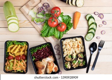 cooked pasta, chicken wings, fried eggplants nto lunch boxes, raw vegetables set, top view - Shutterstock ID 1390928909