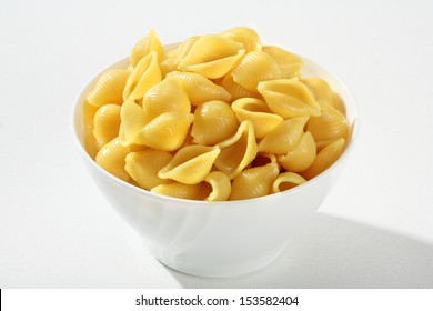 Cooked Pasta Shells / A Portion Of Cooked Pasta, Served Without Sauce On A White Ceramic Bowl Against A White Backdrop 