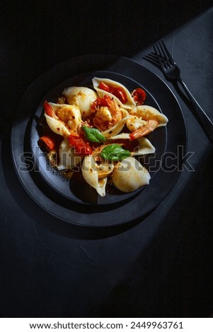 Cooked pasta shells and prawns overhead shot on black background moody