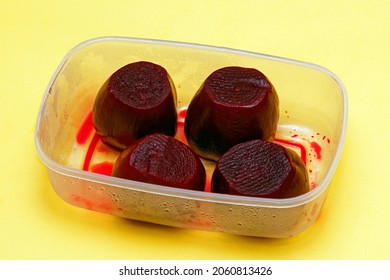 Cooked and peeled beetroot in plastic box on yellow background