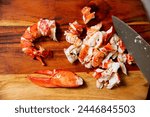 Cooked red lobster meat on a wooden cutting board. Knife and cut into pieces tail and claws on wooden surface