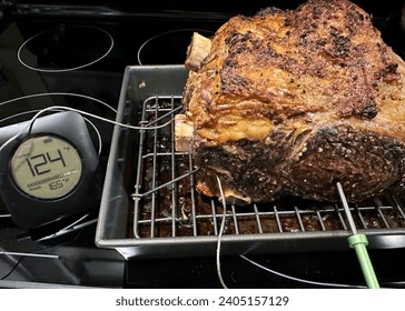 Cooked rib roast with an inserted thermometer resting to get to a medium rare