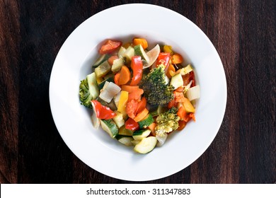 Cooked Roasted Vegetables Stewed Tomatoes, Carrots, Peppers, Courgettes, Brocoli, Onion On Plates