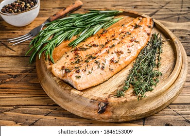 Cooked salmon fillet with herbs and pink pepper. wooden background. Top view